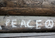 Weiße Schrift Peace und Peace-Zeichen auf Holz geschrieben